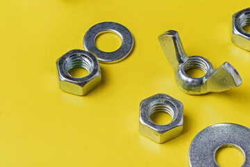 Metal nuts and washers on a yellow background close-up