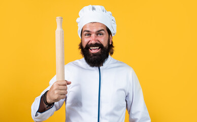 mature bearded man wear chef hat hold rolling pin. male cook ready for preparing food. brutal hipster in apron going to be cooking meal. time for eating. happy baking. concept of housekeeping