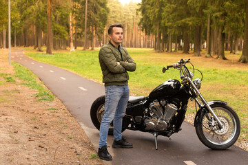 Fototapeta na wymiar Happy young man stands on the road, motorbike
