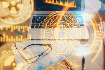 Computer on desktop in office with technology theme hologram. Double exposure. Tech concept.