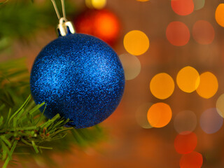 Blue Christmas ball on Christmas tree with blurred background of garlands