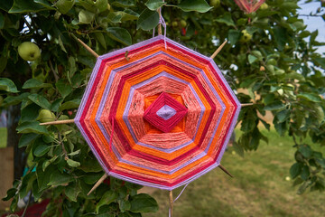 Colorful octagon made from threads. The decoration on the tree at the festival. 