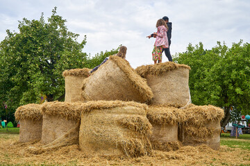 Naklejka na ściany i meble Children are playing on the haystacks in the garden 