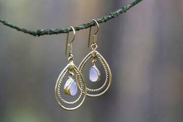 Fototapeta na wymiar Elegant brass earrings with beautiful gemstone on forest branch