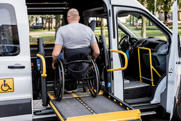 A man in a wheelchair on a lift of a vehicle for people with disabilities