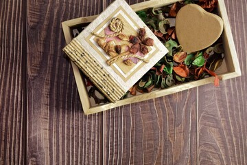 On rustic boards, in a wooden box, colored dry leaves, a small handmade notebook and a cardboard heart