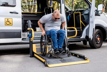 A man in a wheelchair on a lift of a vehicle for people with disabilities