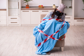 Young sick man watching tv at home in pandemic concept