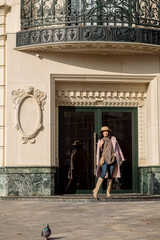 beautiful caucasian brunette woman in a stylish outfit walking down the street in the offseason in a coat and hat
