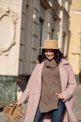 beautiful caucasian brunette woman in a stylish outfit walking down the street in the offseason in a coat and hat
