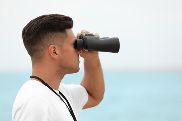 Obraz premium Handsome male lifeguard with binocular near sea