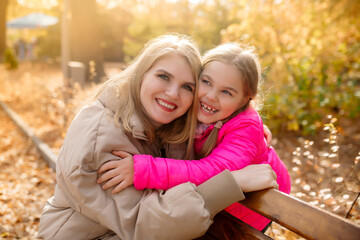 Caucasian beautiful family mom and little daughter on a walk in the park in autumn in October
