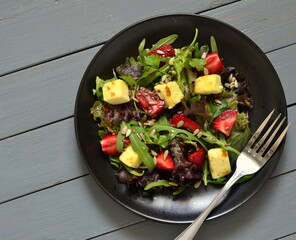 Leaf salad with strawberries, cheese and seeds, top view, copy space