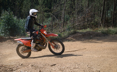Homem a andar de mota de todo o terreno na montanha - de pé em equilíbrio - mota vermelha - motocross