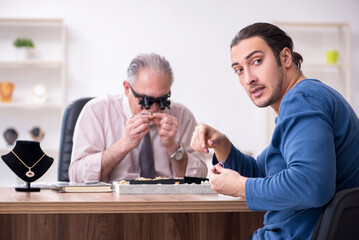 Young man visiting old male jeweler