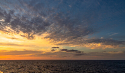 Sunset and dramatic set of clouds drifting over the tropical waters of the Caribbean Sea are lit by the last moments of daylight.