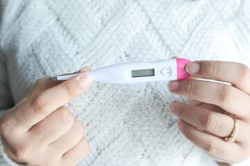 close up of women hand holding digital thermometer.