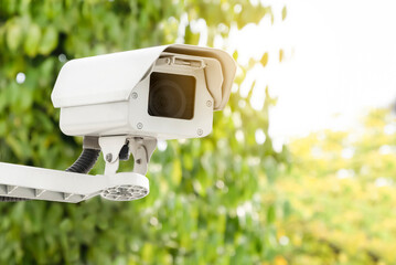 Modern public CCTV camera with blurred natural background. Intelligent reccording cameras for monitoring all day and night. Concept of surveillance monitoring with copy space and clipping path.