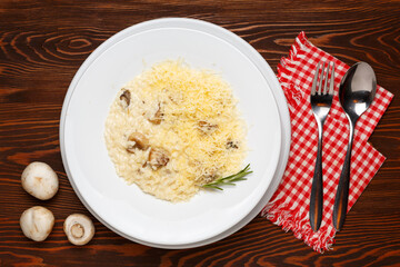 Mushroom risotto on a white plate on a dark wooden table.