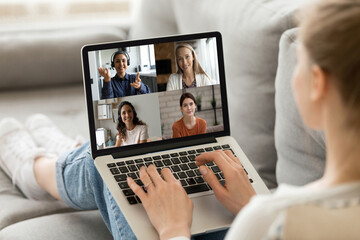 Fototapeta na wymiar Close up rear view woman engaged in virtual conference with diverse colleagues, sitting on couch, businesswoman talking with colleagues by video call, internet negotiations, brainstorming from home