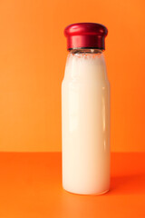 close up of bottle of milk on orange background 