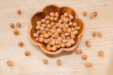 Hazelnut. Hazelnut in a wooden bowl and sprinkled on a wooden table. Wooden bowl with nuts.