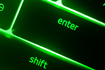 Hazy green illuminated keyboard enter and shift key closeup