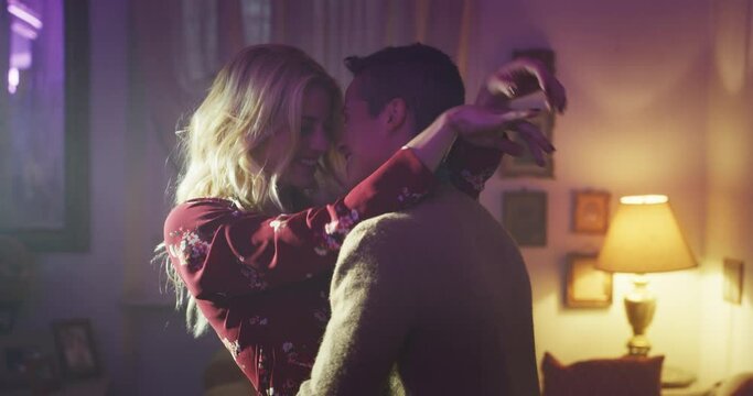Cinematic shot of carefree happy romantic homosexual female gay and transgender man couple in love is enjoying time together is hugging and kissing with passion as sign of timeless forever love.