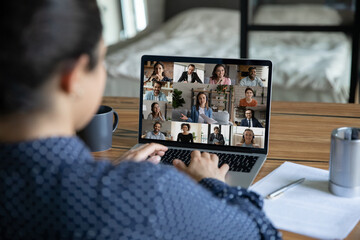 Rear view close up Indian businesswoman chatting with colleagues by video call, diverse business people on laptop screen, employees group discussing project, sharing ideas, online meeting, briefing