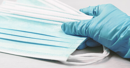 close up of doctor's hand in a glove with a medical face mask for protection against infection. Coronavirus, ppe, personal safety and lockdown measures. Medical and healthcare banner