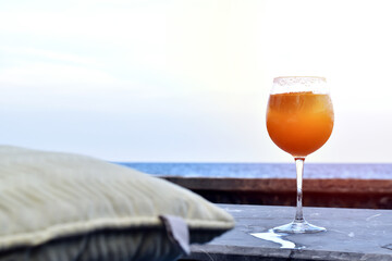 Orange juice in a tall glass, The outdoor atmosphere has a blurry sea in the background.