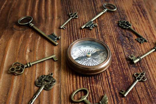 Image of old antique keys and compass over wooden background. Top view, flat lay