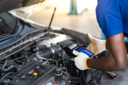 Expertise mechanic working in automobile repair garage. battery inspection. Battery Capacity Tester Voltmeter