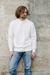 Man wearing white sweatshirt or hoodie for mock up, logo designs or design prints with with free space among europe city streets.