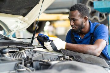 Professional car mechanic repair service and checking car engine by Diagnostics Software computer....