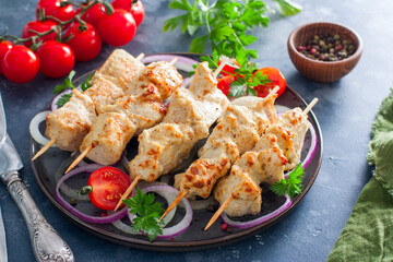 Chicken breast kebab baked in the oven on wooden skewers on a plate, horizontal