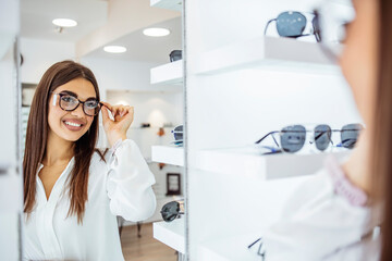 Shot of a young woman trying on a new pair of glasses at an optometris. Deciding which pair fits...
