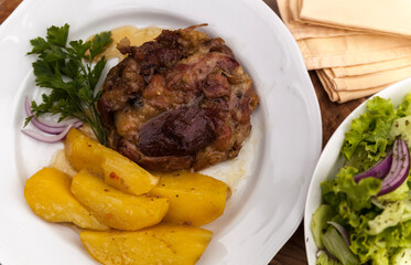 Rasted pork with potatoes served on a plate with salad