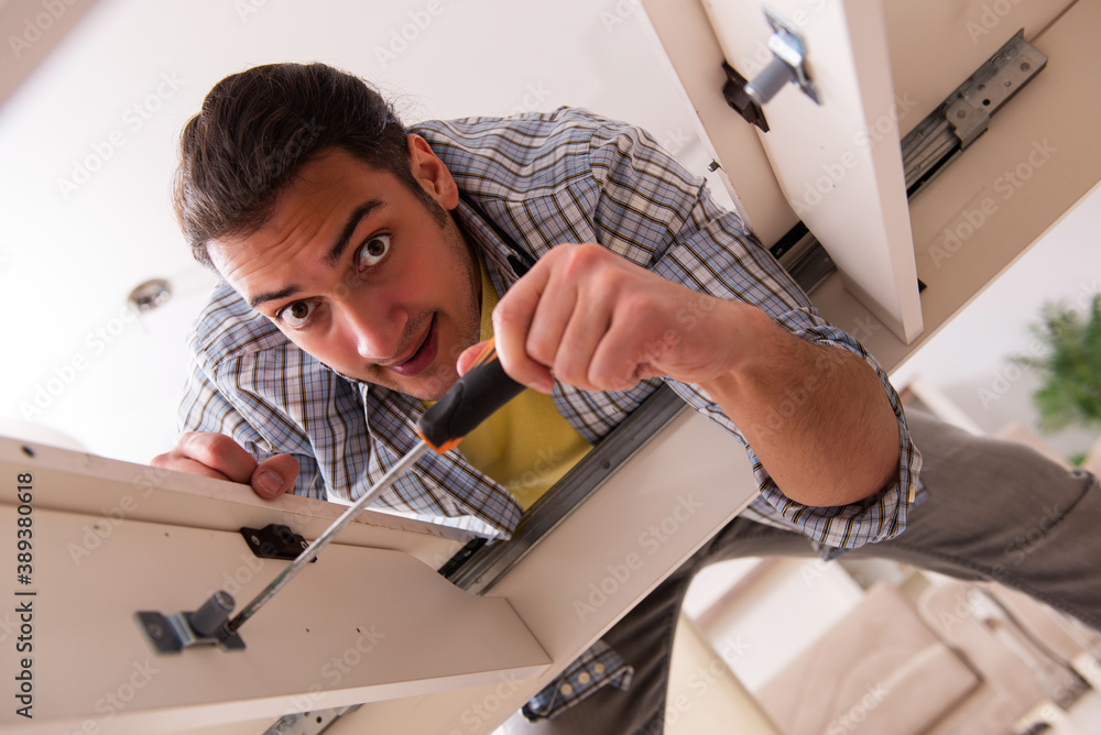 Wall mural Young male carpenter repairing furniture at home