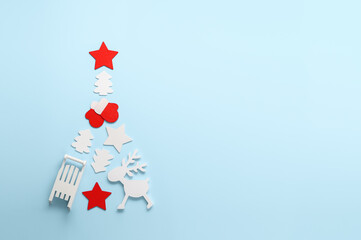 Alternative Christmas tree. Top view of Christmas tree made from different wooden decoration on pastel blue background. Copy space, flat lay.