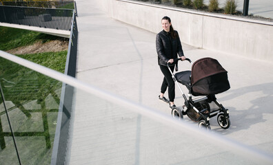 Mother with a pram or stroller on modern city streets walking and relaxing in autumn