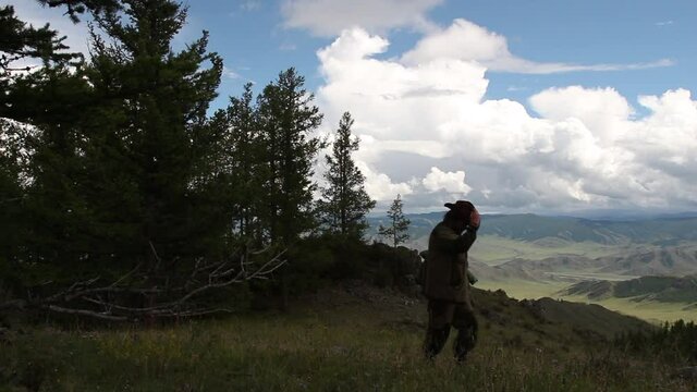  man european with  cowboy hat walks in  clearing against the backdrop of mountains as  traveler