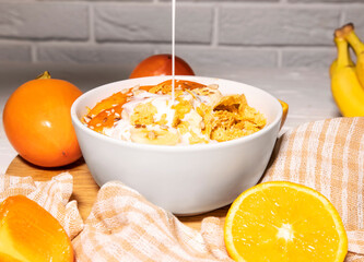 Corn Flakes Bowl with Milk, Persimmon, Orange and Wooden Spoon on white background, Healthy Breakfast