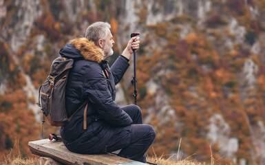 Happy mature man on a hiking resting on a bench and enjoy the view