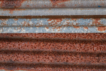 Sharp edges of the rusty metal sheets placed on the floor. Old aged weathered rusty galvanized corrugated iron sheet roof of abandoned mood. selective focus blur background. Vintage.