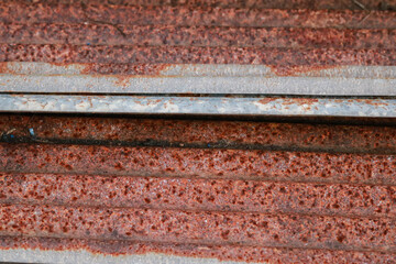 Sharp edges of the rusty metal sheets placed on the floor. Old aged weathered rusty galvanized corrugated iron sheet roof of abandoned mood. selective focus blur background. Vintage.