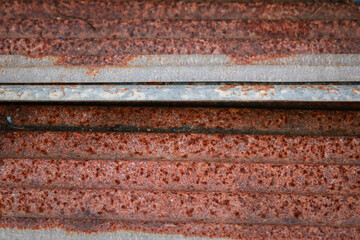 Sharp edges of the rusty metal sheets placed on the floor. Old aged weathered rusty galvanized corrugated iron sheet roof of abandoned mood. selective focus blur background. Vintage.
