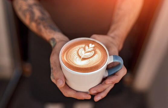 Barista holding cup of coffee with latte art