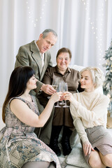 Celebration, family, generations and holidays concept. Senior happy couple clinking champagne glasses with their young pretty two granddaughters, celebrating New Year or Christmas