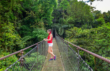 Arenal Hanging Bridges, young woman hiking in green tropical jungle, Costa Rica, Central America.